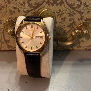 Gold tone face with brown leather strap. Battery required.
